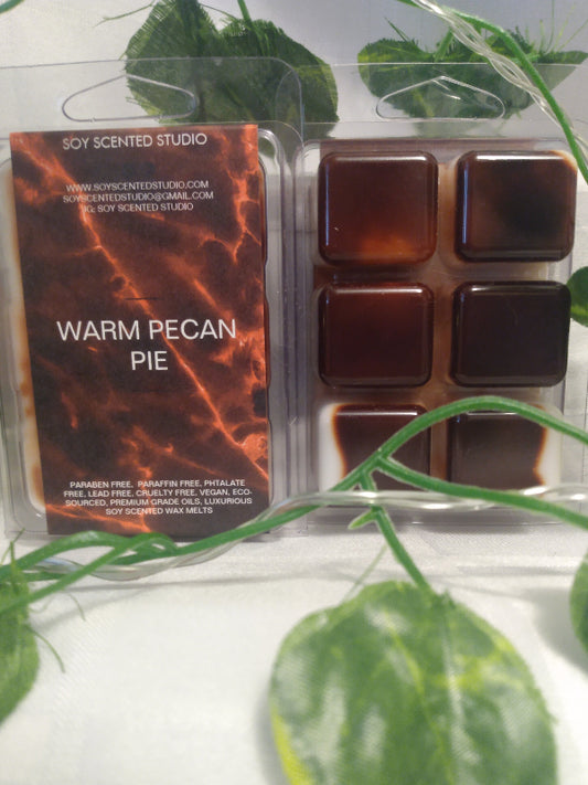 Packaged soy scented wax melts with 'Warm Pecan Pie' scent in front of green leaves